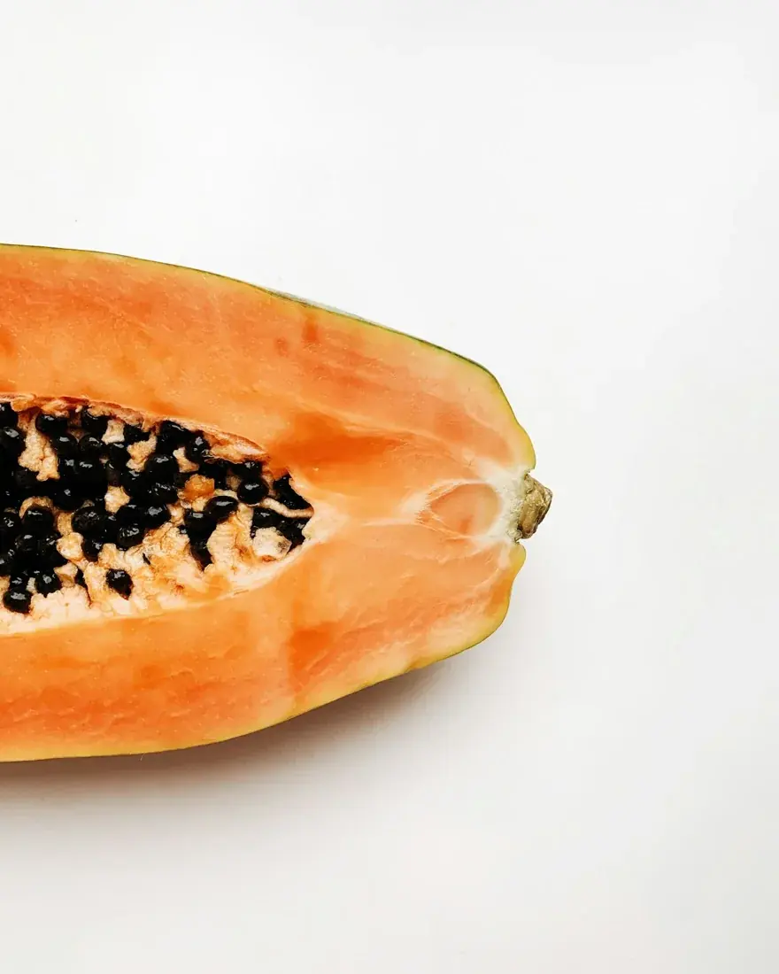 A halved orange-fleshed papaya with black seeds.