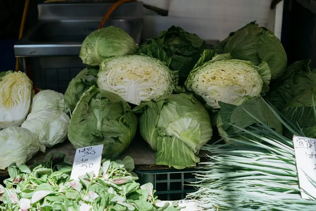 Whole and halved fresh green cabbages at a market