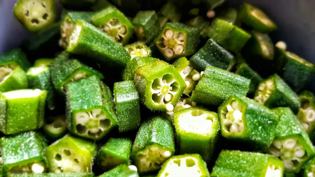 Fresh green okra pods, including cut pieces, in a basket